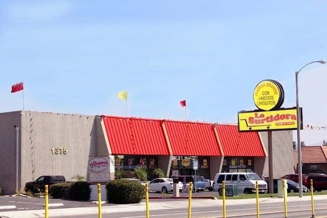 A yellow and red restaurant with cars parked in front of it.